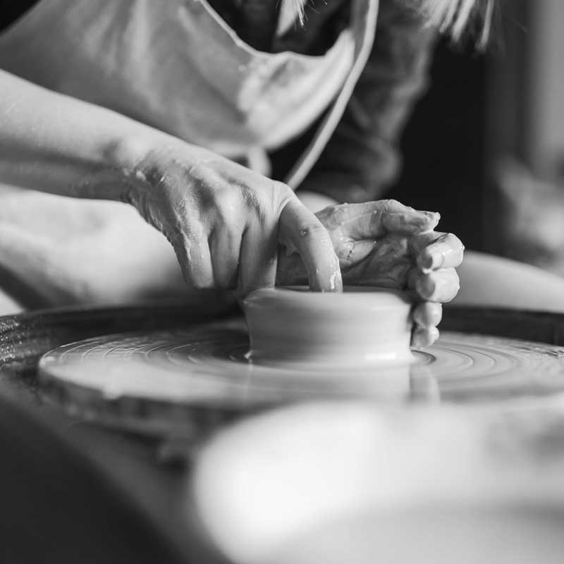 Photo en noir et blanc montrant des mains en train de façonner une poterie sur un tour de potier. L'image vise à illustrer l'art du SEO.