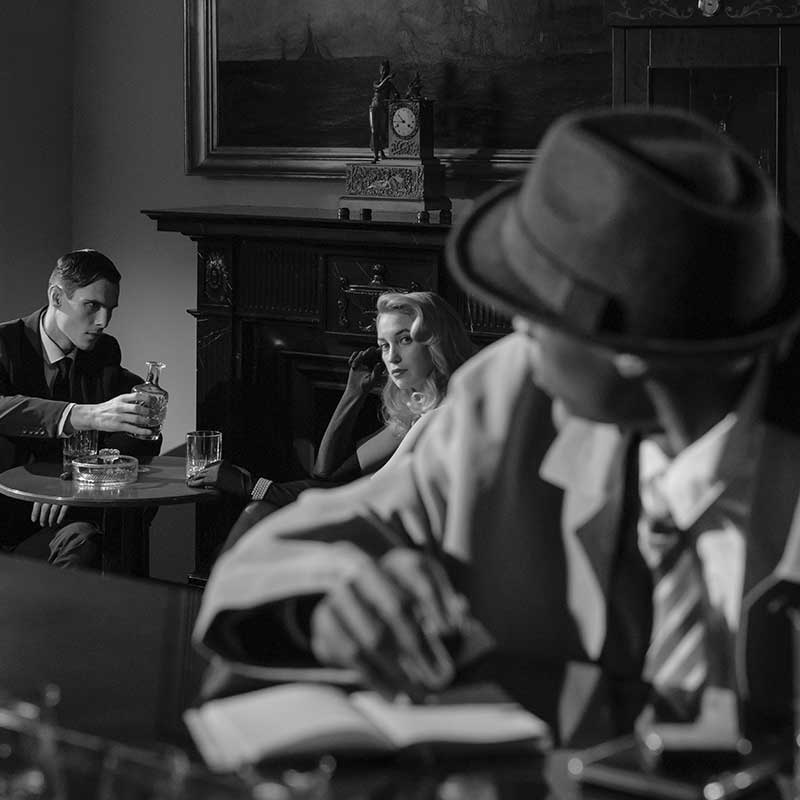 Photo en noir et blanc montrant un détective en train de surprendre une conversation